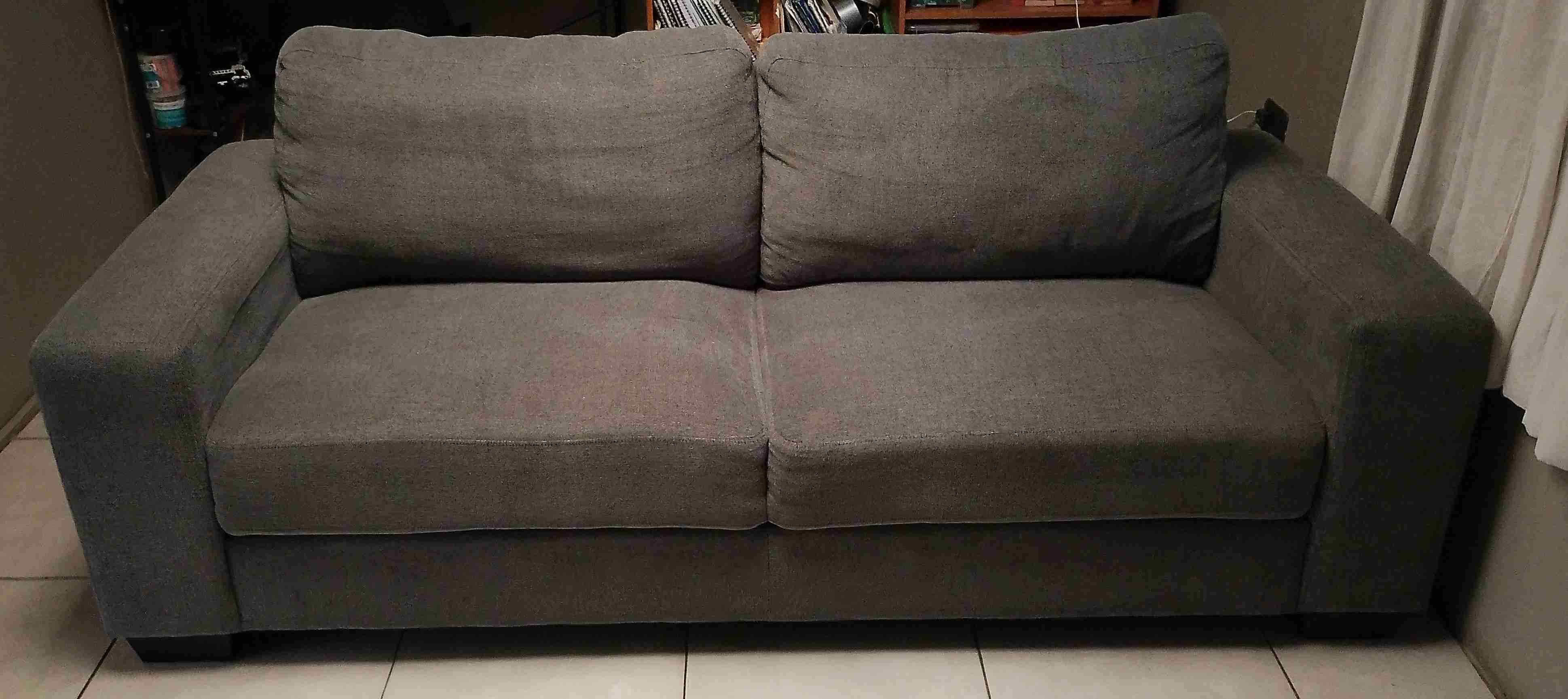 Sofá gris de tres cuerpos con resortes.